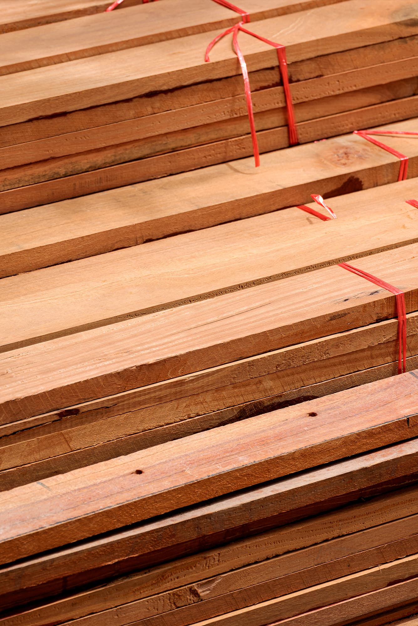 Sztaple dociętych na wymiar desek paletowych spiętych taśmą transportową, gotowych do wysyłki z tartaku do producenta palet.